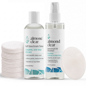 Almond Clear skincare set featuring a Full Spectrum Toner bottle, a Universal Oil Cleanser spray bottle, a stack of bamboo facial rounds on the left, and a silicone scrubber on the right, all on a white background.