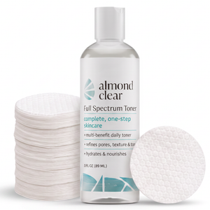 Almond Clear Full Spectrum Toner bottle with a white cap, shown with a stack of cotton pads on the left and a single round cotton pad on the right against a white background.