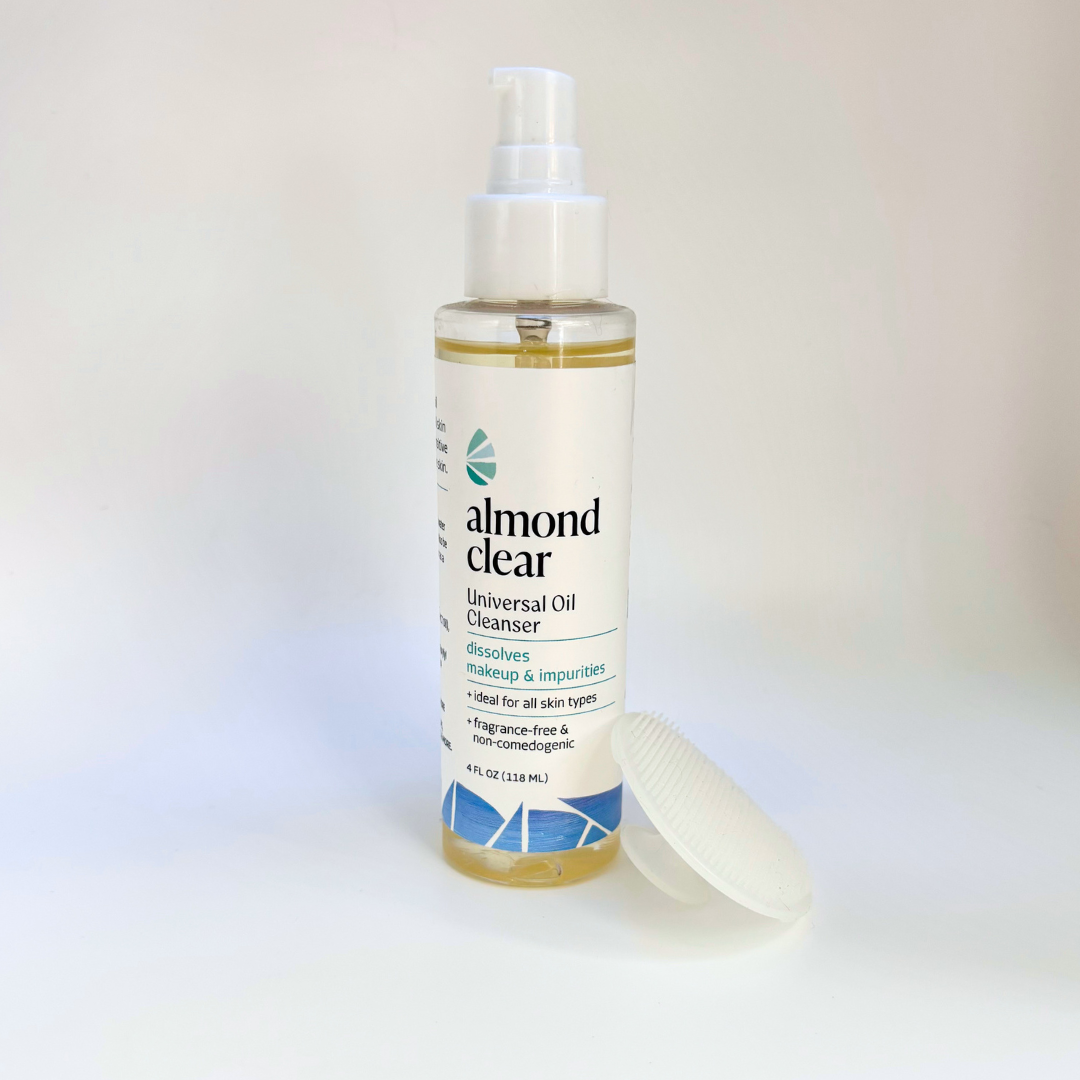 Almond Clear Universal Oil Cleanser in a 4 oz clear bottle with a white pump top, shown on a white background with the silicone facial scrubber next to it.